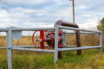 Fototapeta na wymiar Pipe and a red valve pipe near oil pump jacks.
