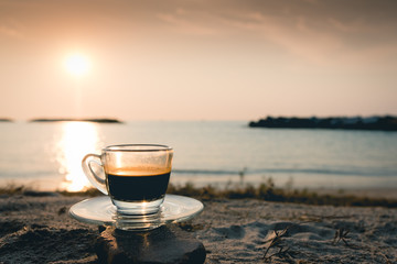 black coffee ready to drink from mug on the beach outdoor picnic..