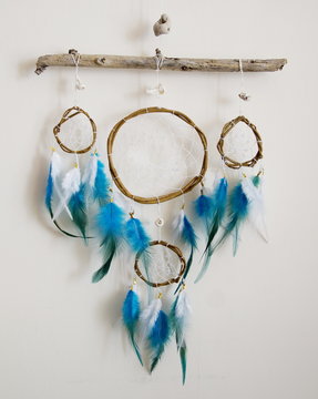 Photo of handmade dreamcatcher with feathers and beads on a white background, ethnic theme