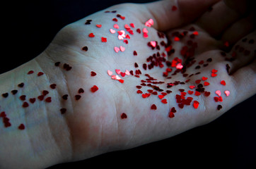 Female hands with small shiny red hearts