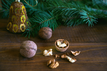 walnuts with shell, fir tree branch and Christmas decoration on rustic wooden background. you can use it for a greeting card or voucher. Copy space for text. Nature New Year concept.