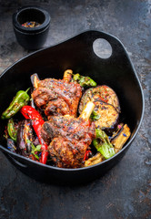 Traditionelle gegrillte Lammhaxe mit Aubergine und Chili als Draufsicht in einem japanischen Modern Design Gusseisen Topf 