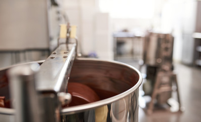Stainless steel mixer stirring melted chocolate in an artisanal workshop