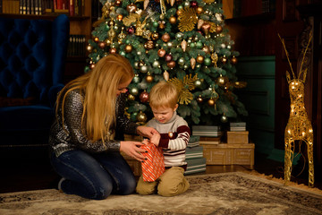 Mother and son playing on the floor next to a nicely decorated Christmas tree