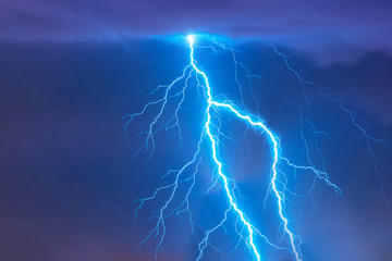 Bright flash of lightning strike during a night thunderstorm in the sky.