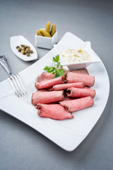 Traditionelle kalte Platte mit aufgeschnittenem Roastbeef  und Remoulade als closeup auf einem Modern Design Teller