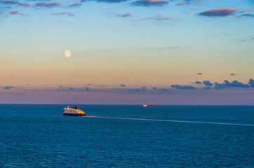 Ships crossing the English Channel at twilight under a full moon