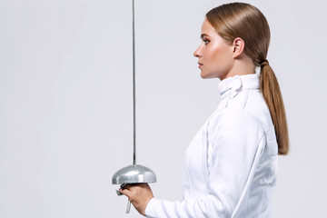 Young fencer athlete wearing fencing costume holding the sword and mask. Isolated on white background