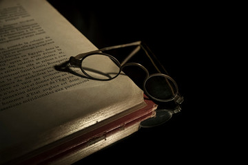 Closeup very old specacles eyes glasses on very old open book lying on mirror for reflection