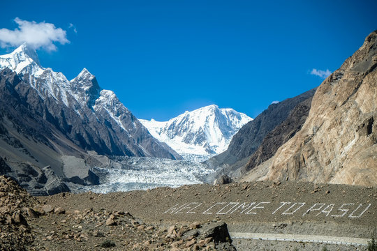 Passu glacier with text 'Welcome to PASU', surrounded by mountains in Karakoram range. Passu, Gilgit Baltistan, Pakistan.