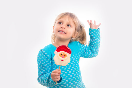 Beautiful little girl holding a candy in the form of Santa Claus