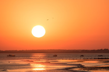 Warm orange sunset with huge sun at atlantic ocean coastline