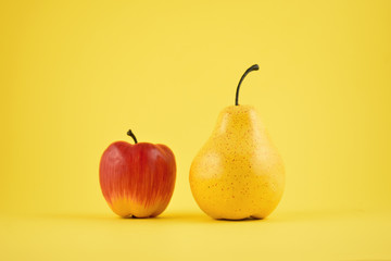 Pear and apple decoration stock images. Yellow pear and red apple on a yellow background. Fruit home decor. Plastic decorative fruit