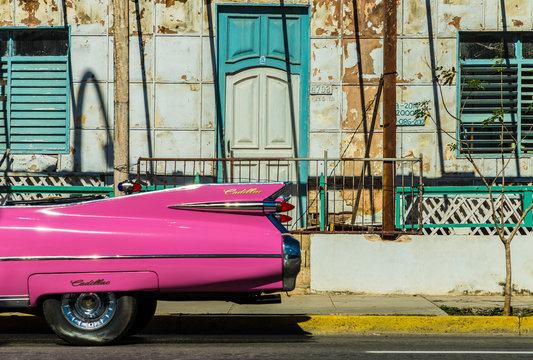A classic American car driving past an old building in Varadero, Cuba