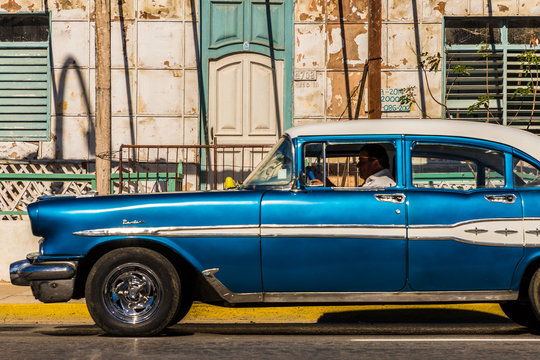 A classic American car driving past an old building in Varadero, Cuba