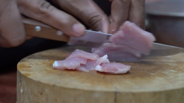 The chef cuts raw meat with the knife, Dolly shot
