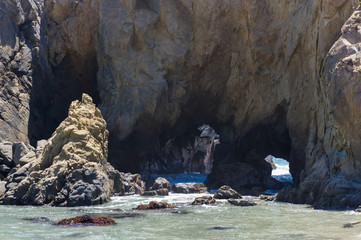 Big stone with hole at ocean beach in nature.