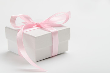 White gift box on a white background with a pink ribbon. Birthday present, Women's Day or Christmas