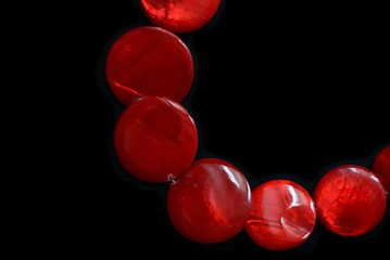 Red necklace from round flat beads on a dark background close up