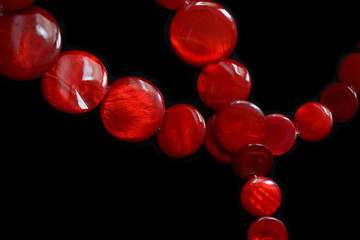 Red necklace from round flat beads on a dark background close up