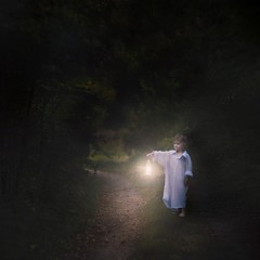 Surreal scene with small boy walking in night with lantern