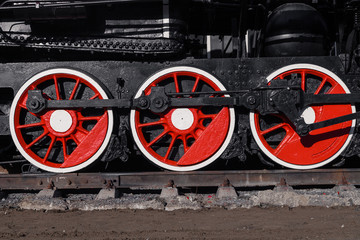 Old black, white and red locomotive is standing on the rails in a railway museum against a blue sky. Concept of history, the carriage of passengers, transport