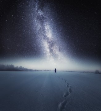 Starry night sky and man silhouette standing on snow