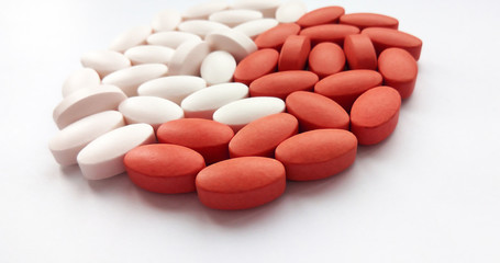Assorted red and white pharmaceutical medicine pills and tablets on white background. Pharmacy theme, health care, drug prescription for treatment medication and pharmaceutical medicament