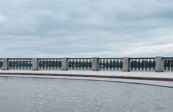 Decorative fence over the water on a background of cloudy sky