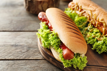 Tasty hot dogs with salad on wooden table