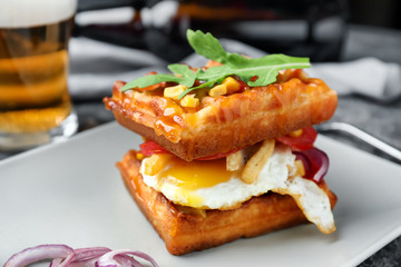 Delicious waffles with fried egg on plate, closeup