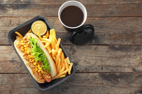 Tray With Tasty Hot Dog, French Fries And Coffee On Wooden Table