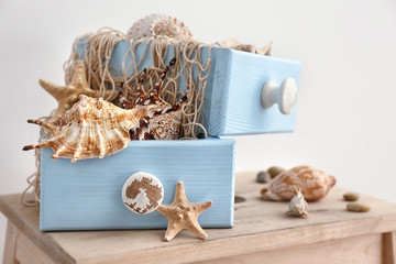 Drawers with net and seashells on wooden table