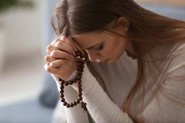 Beautiful young woman praying at home