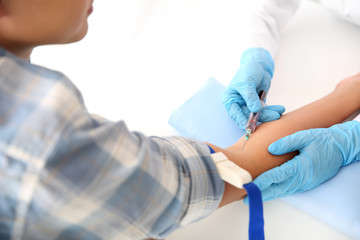 Doctor taking blood sample from vein in hospital