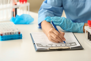 Female doctor working with blood samples at table in laboratory