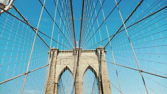 Walk on the Brooklyn Bridge. Pylons and ropes of the bridge against the serene blue sky. Pov video