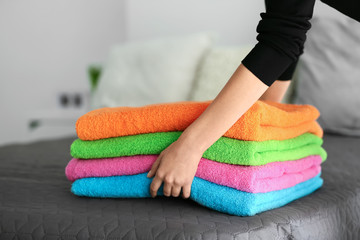 Woman putting stack of clean towels on bed