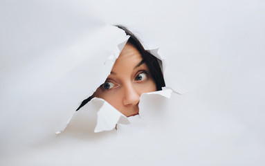 A curious female look. Spying on or overhearing the concept. Hole on White paper.