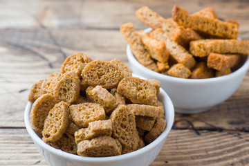Croutons of grain bread with spices in the dishes. Wooden background.