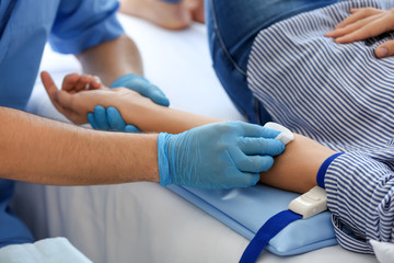 Male nurse preparing female donor for blood transfusion in hospital