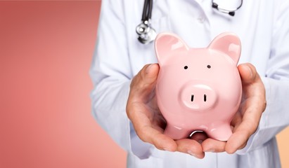 Doctor with Stethoscope Holding Piggy Bank
