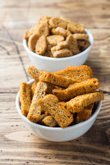 Croutons of grain bread with spices in the dishes. Wooden background.