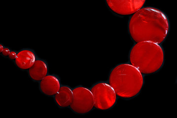 Red necklace from round flat beads on a dark background close up