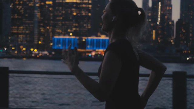 TRACKING Attractive mid-30s Caucasian listening to music while jogging in NYC, Downtown Manhattan in the background. 4K UHD