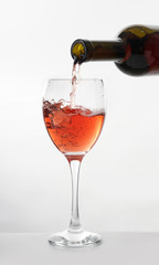 Pouring of tasty wine from bottle into glass on white background