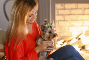 Woman with cute dog resting near fireplace