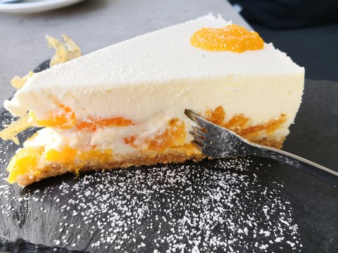 Mandarinenkuchen mit Mandarinenscheibe auf schwarzem Schiefer mit Puderzucker