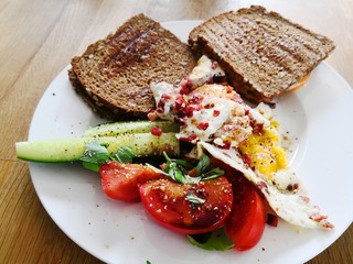 Frühstück und Brunch mit getoastetem Sandwich, Spiegeleiern und Tomaten und Gurken