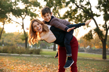 Happy mother and son playing in autumn park
